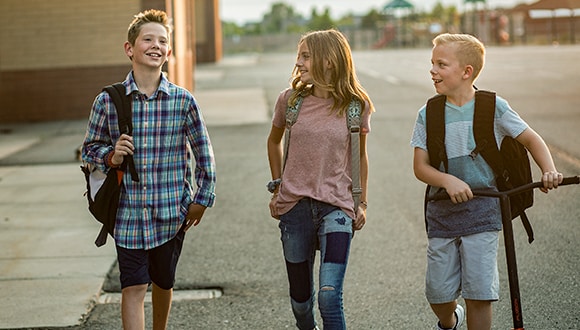 Body image influences all aspects of our lives: 3 young teenagers walking and chatting down a street.