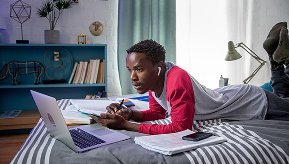 Student laying on his bed studying