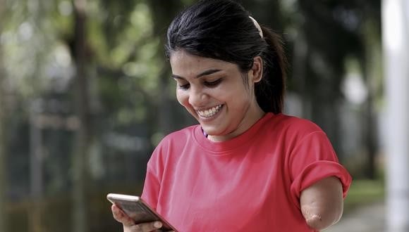 A woman smiling and looking at her phone while navigating online dating