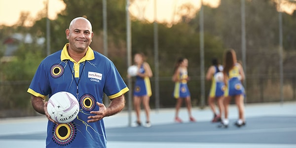 A netball coach training girls at a netball match