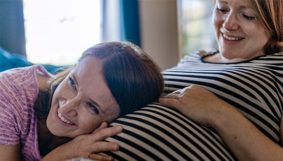 A woman listening to a pregnant womans baby